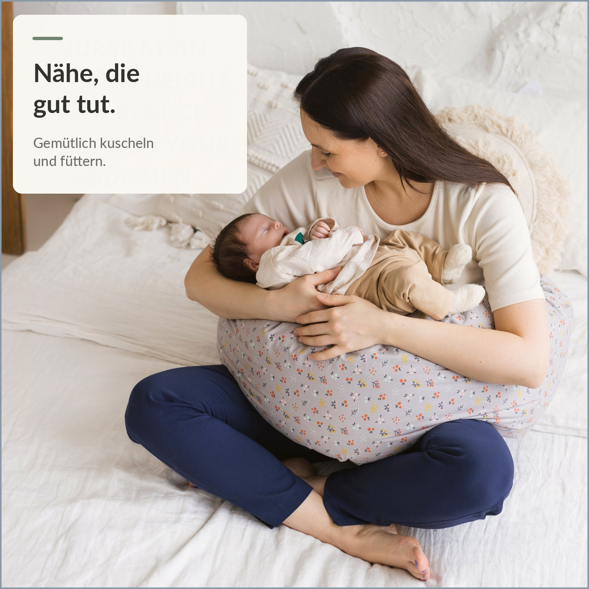 Mutter mit Baby auf dem grauen C-förmigen Still- und Seitenschläferkissen