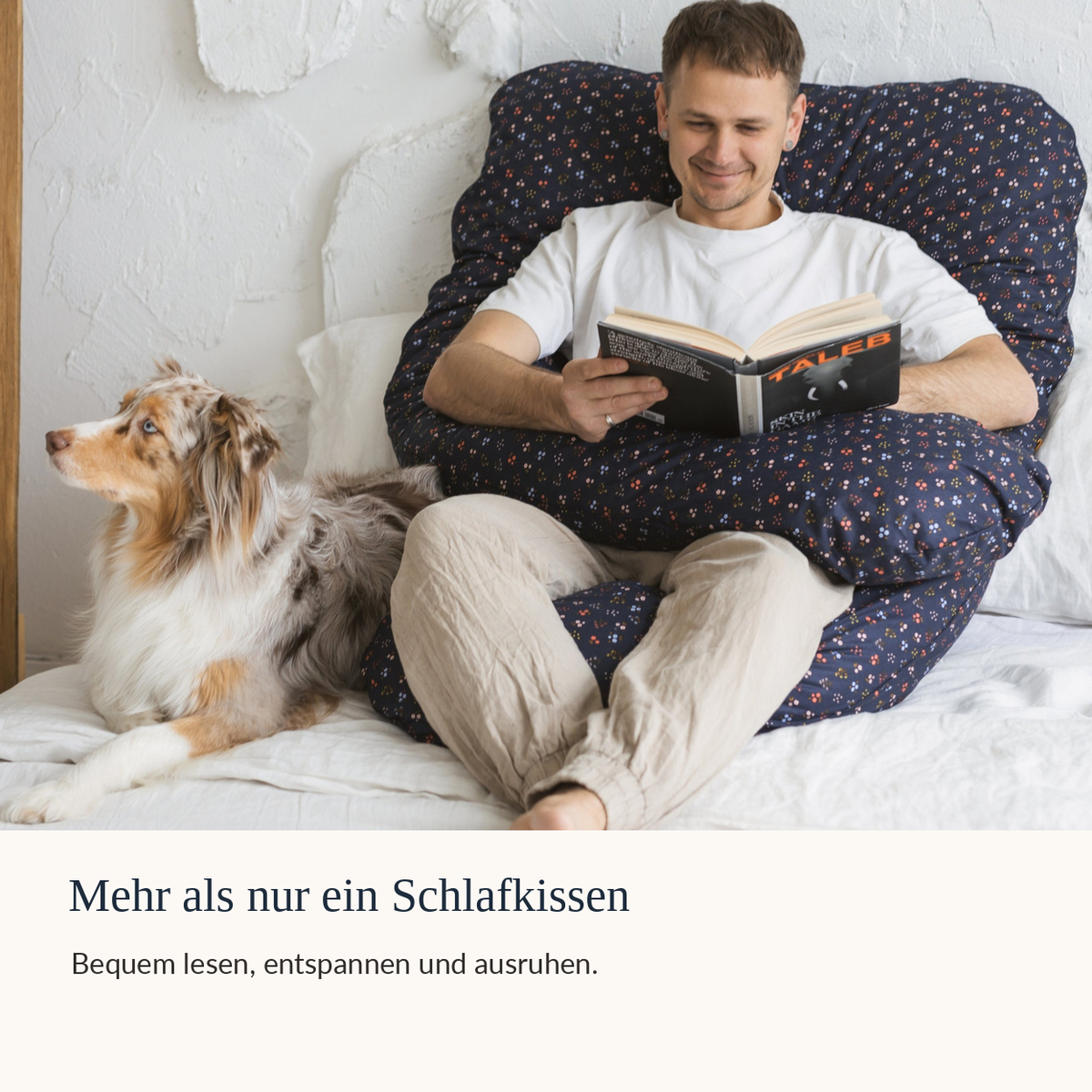 Mann liest im Bett mit Hund und dunkelblauem U-Form Seitenschläferkissen